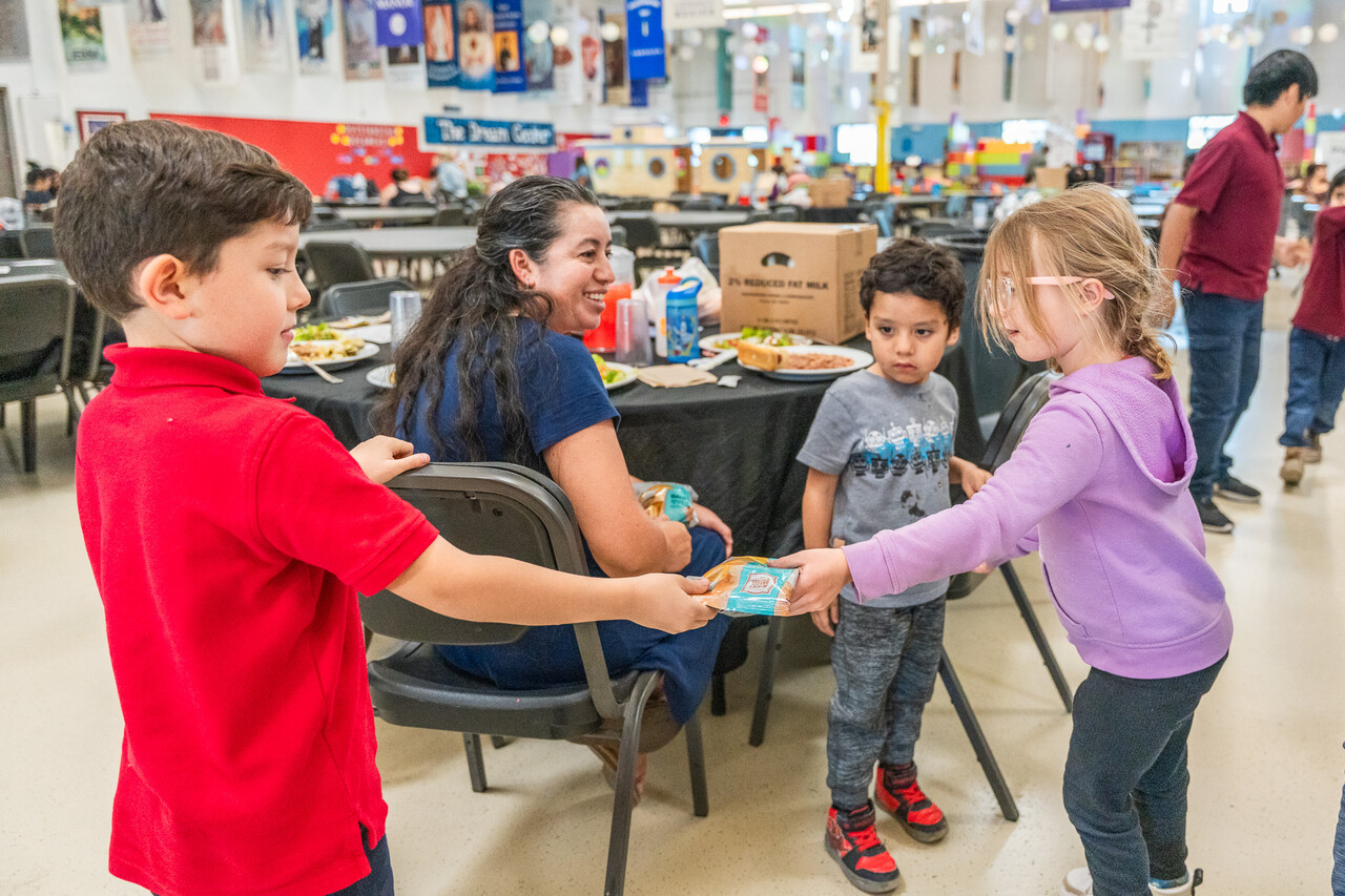Abby hands out food to a family of guests at FEM.