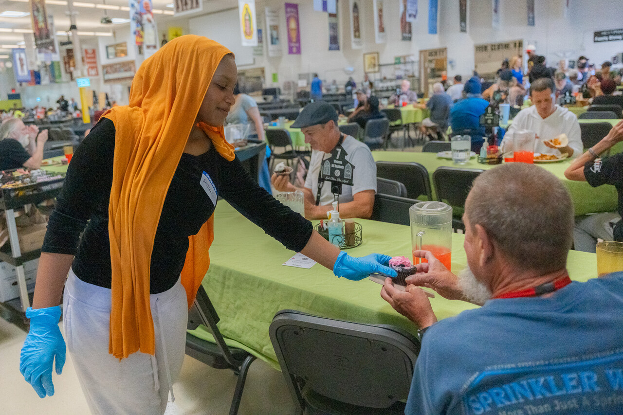 Shifaa hands out dessert to a guest at SVdP's FEM.